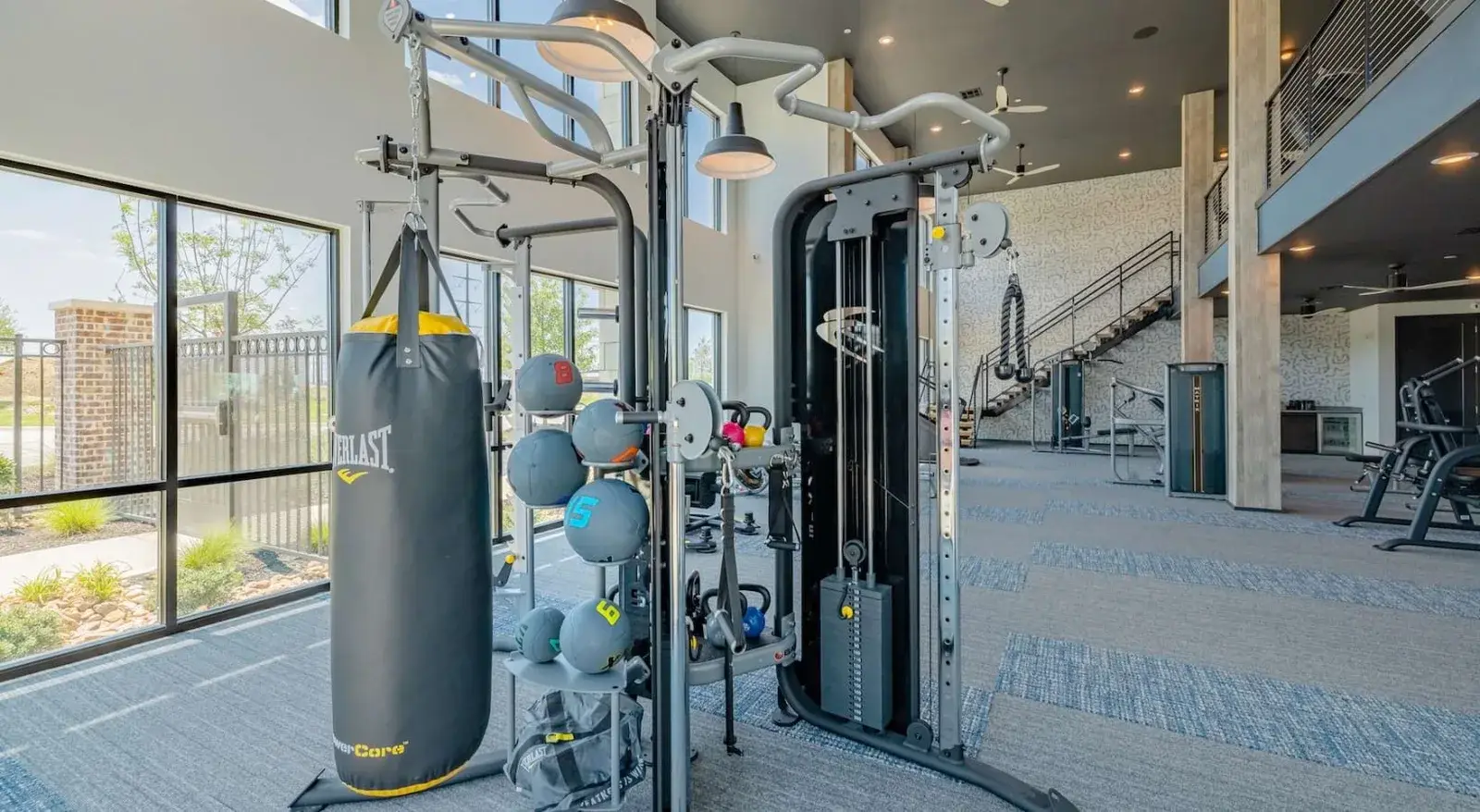 Bright, two-level fitness center with boxing bag, cables, and cardio.