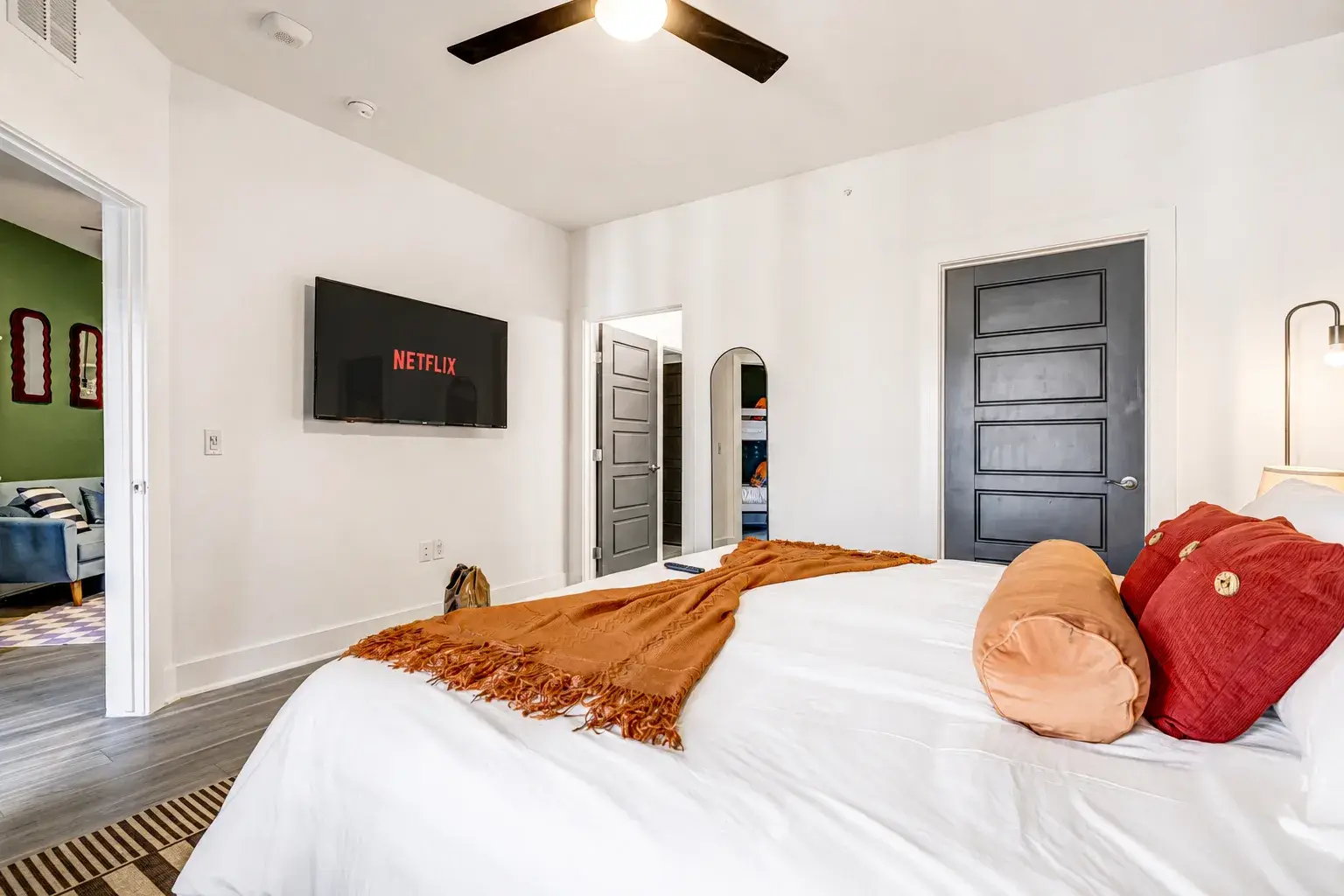 Bright modern bedroom with plush king bed, TV, and stylish warm accents