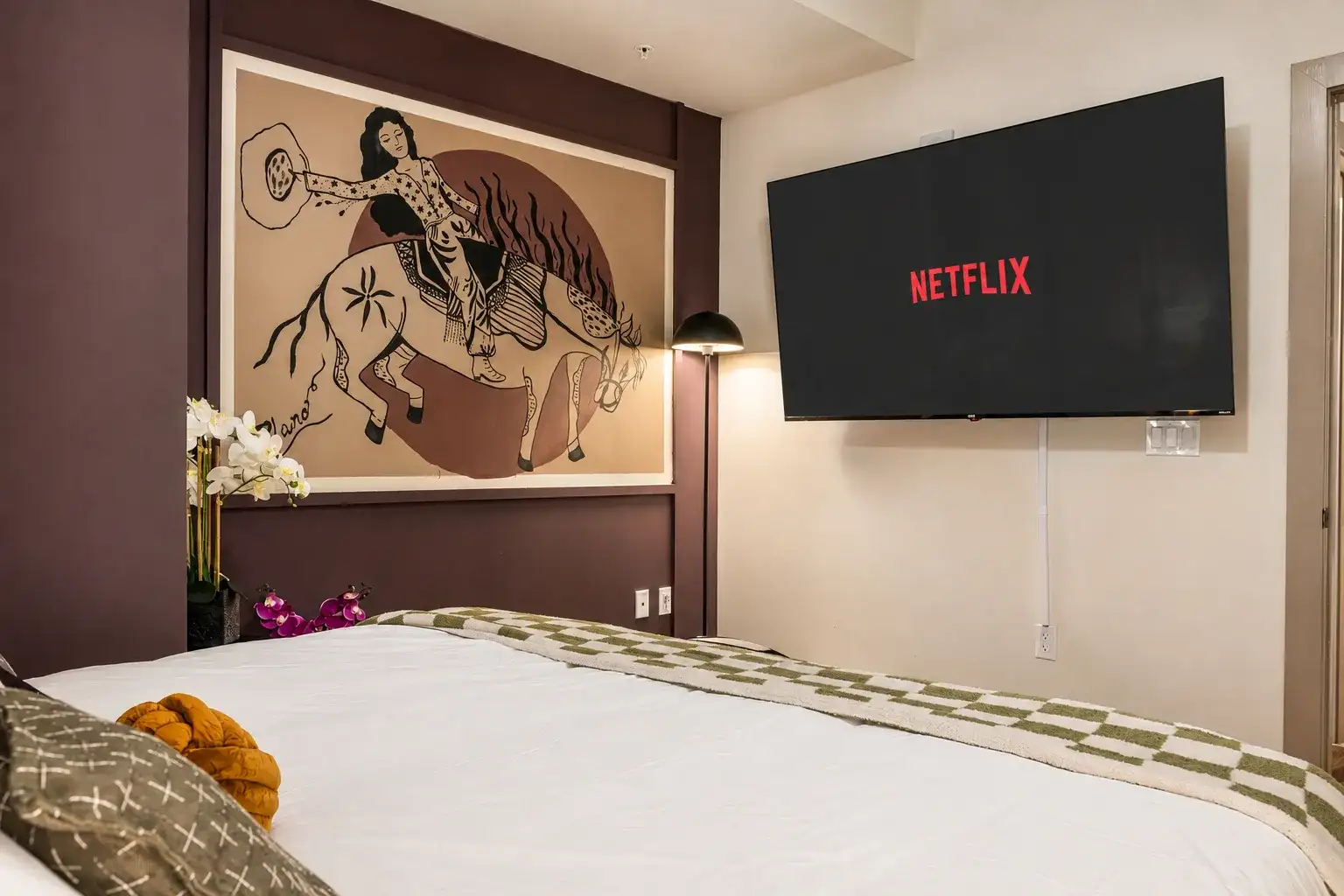 Cozy bedroom with streaming TV, bold artwork, and boutique-style decor