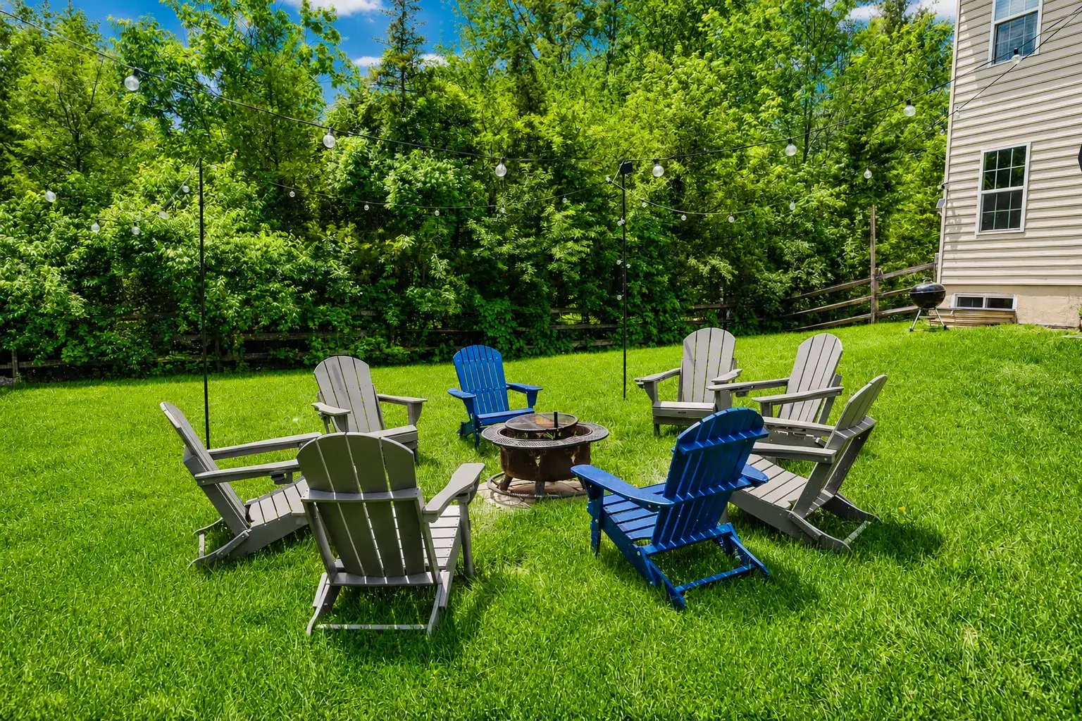 Private backyard fire pit with Adirondack seating and string lights