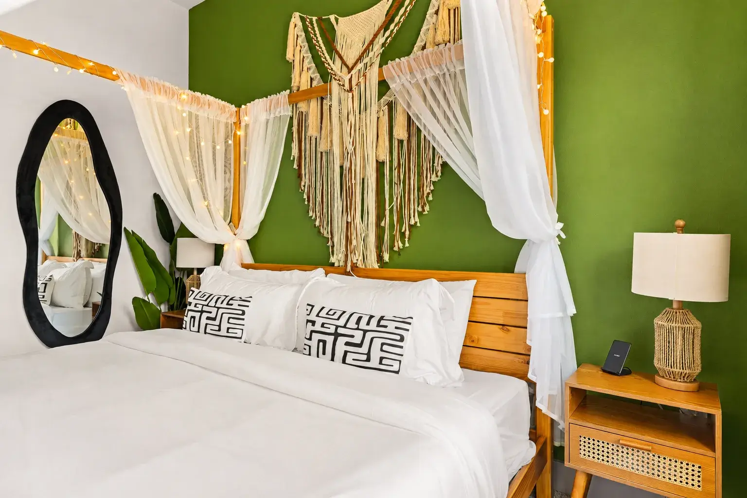 Cozy boho bedroom with canopy drapes, green accent wall, and warm lighting