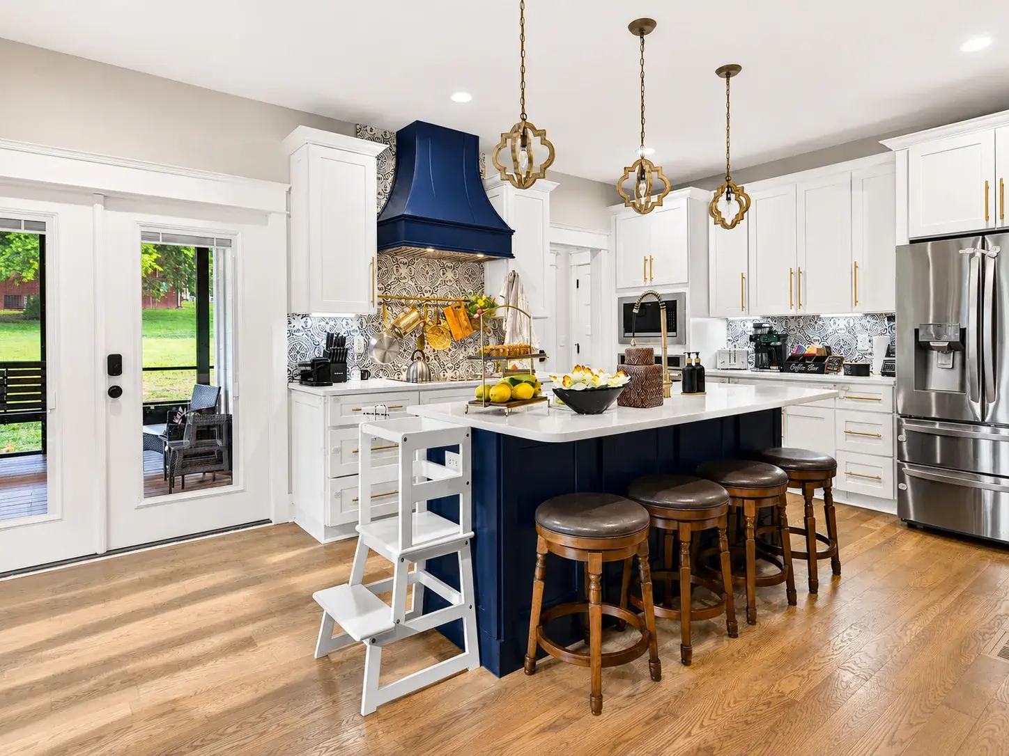 Stylish chef’s kitchen with navy island, designer lighting, and seating for 4
