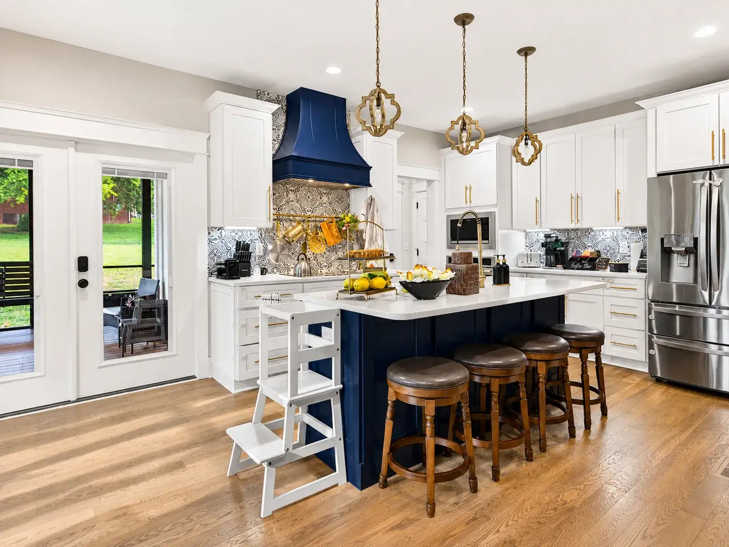 Stylish chef’s kitchen with navy island, designer lighting, and seating for 4