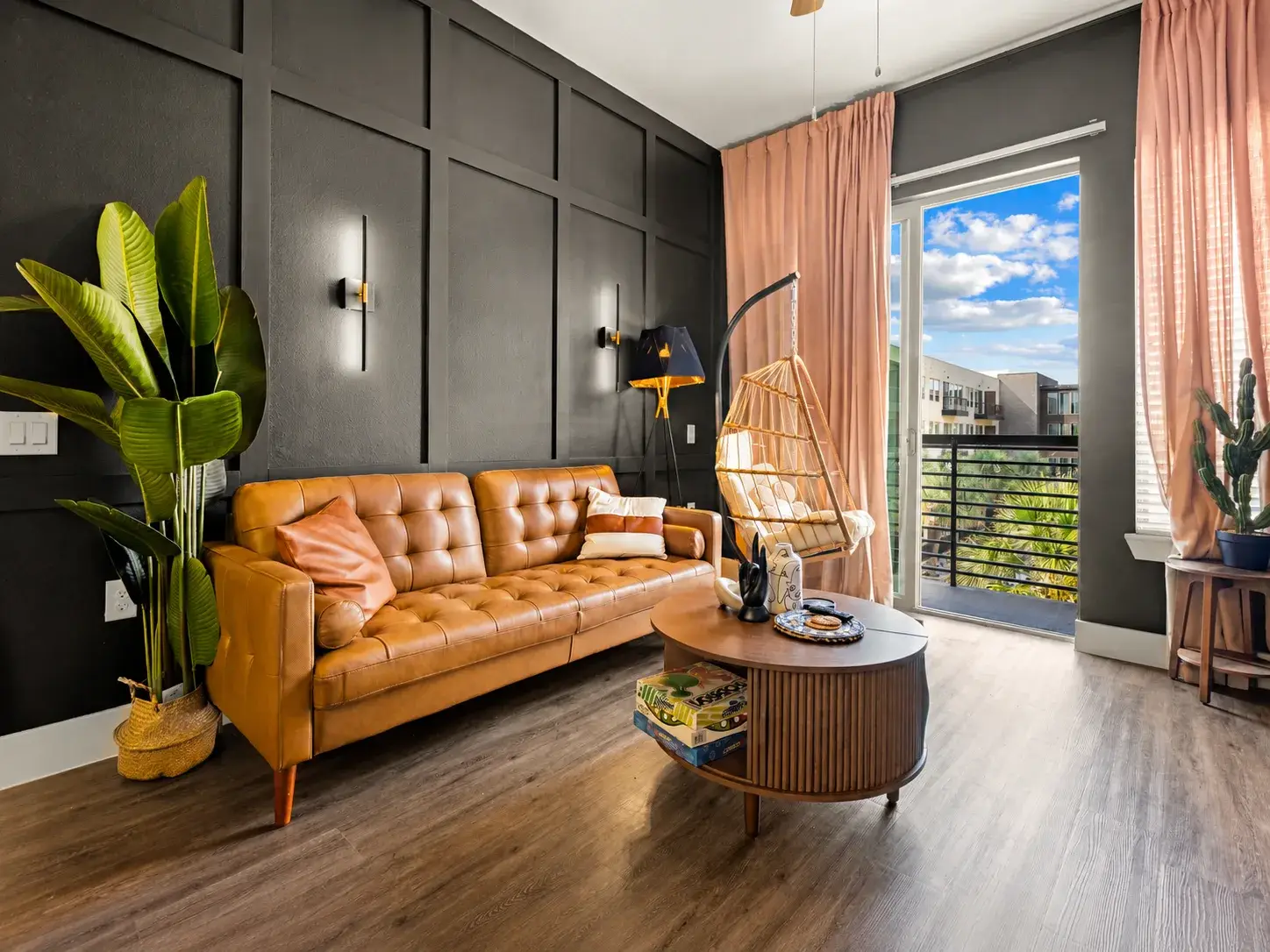 Stylish living room with leather sofa, hanging chair, and bright balcony views