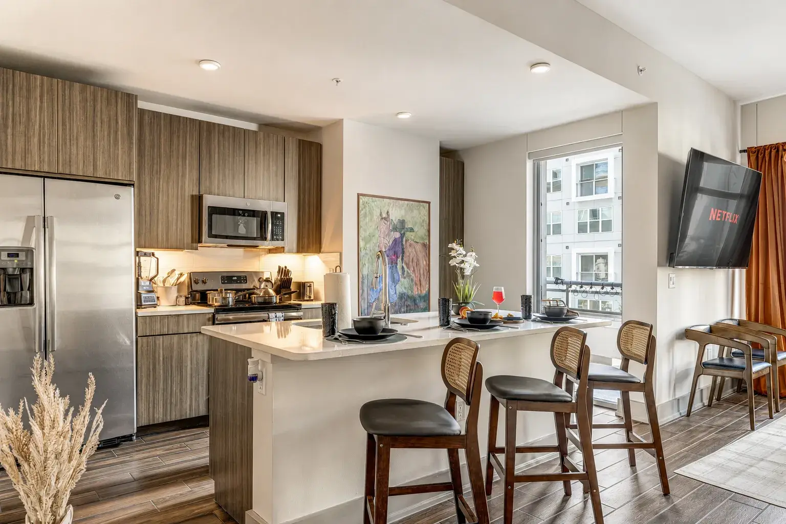 Bright modern kitchen with bar seating, stainless appliances, and TV