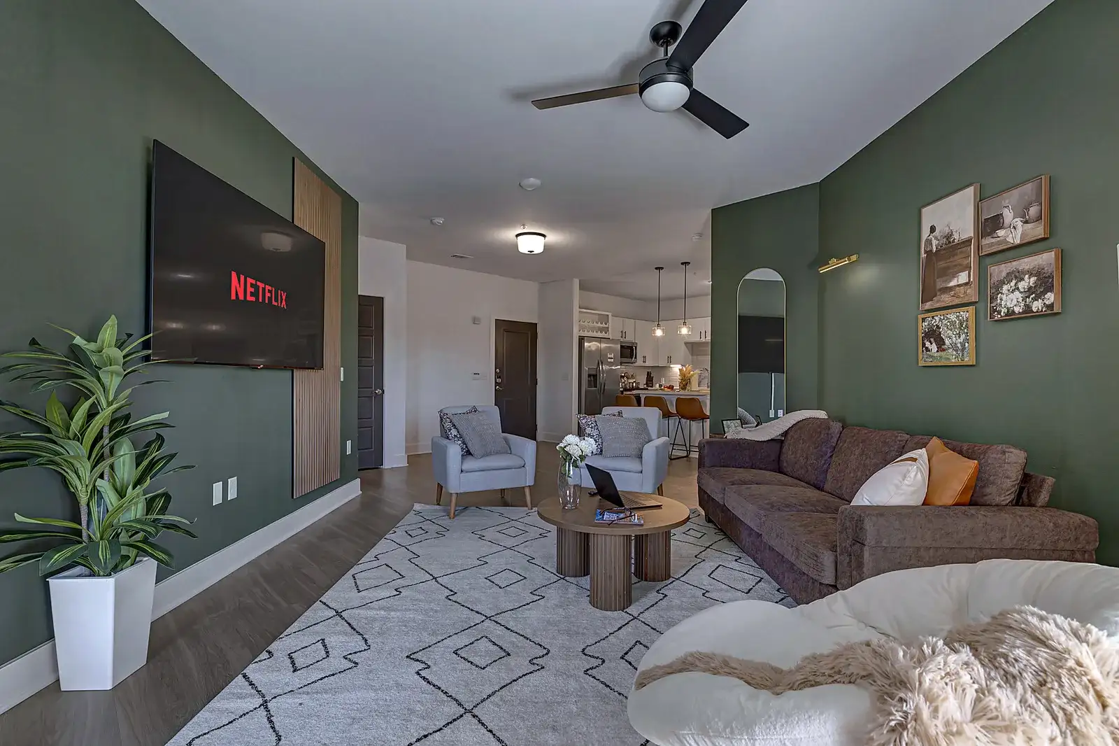 Stylish open living room with big TV, cozy seating, and modern kitchen