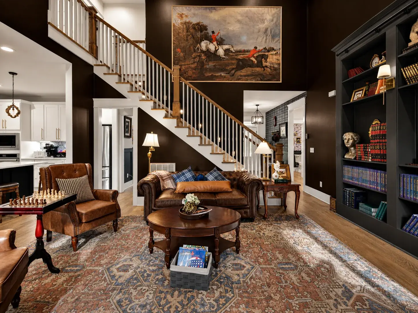 Elegant double-height lounge with grand staircase and cozy leather seating