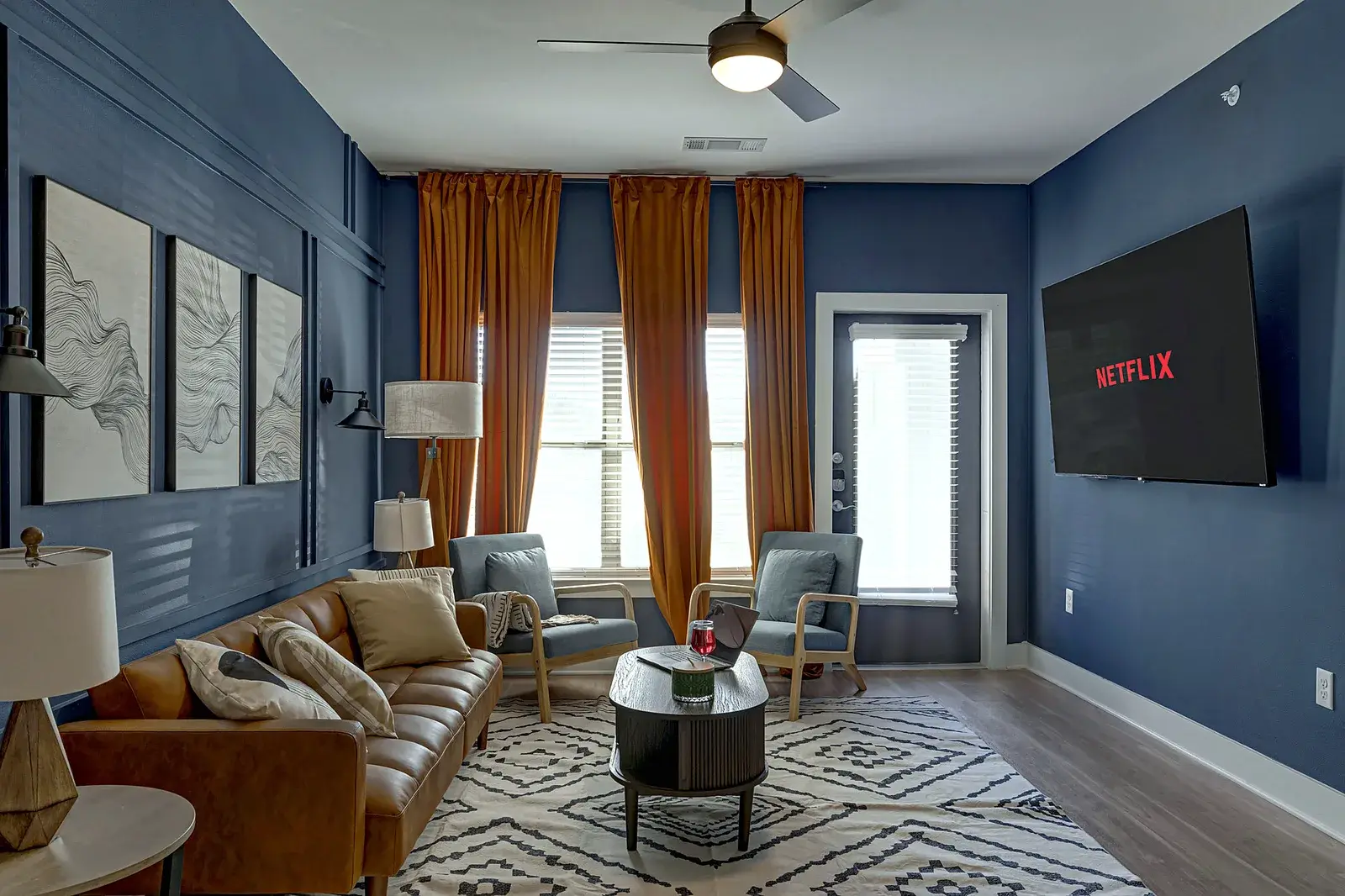 Stylish lounge with bold decor, tall windows, and large TV for cozy nights