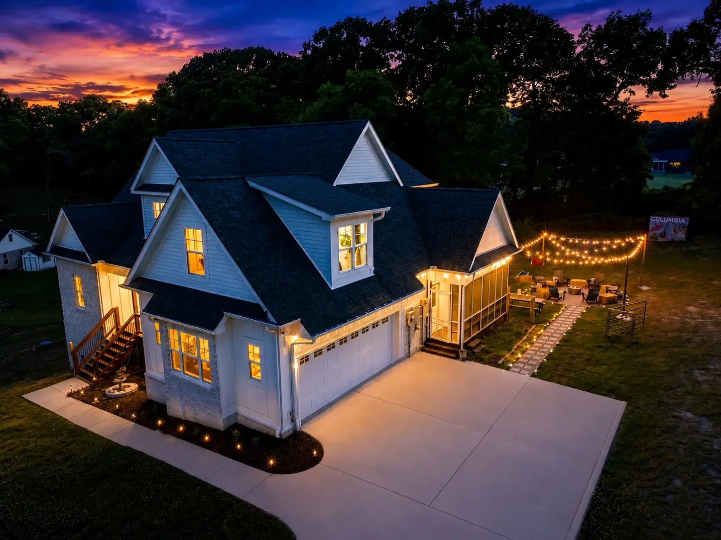 Charming dusk exterior with string-lit patio and spacious outdoor living
