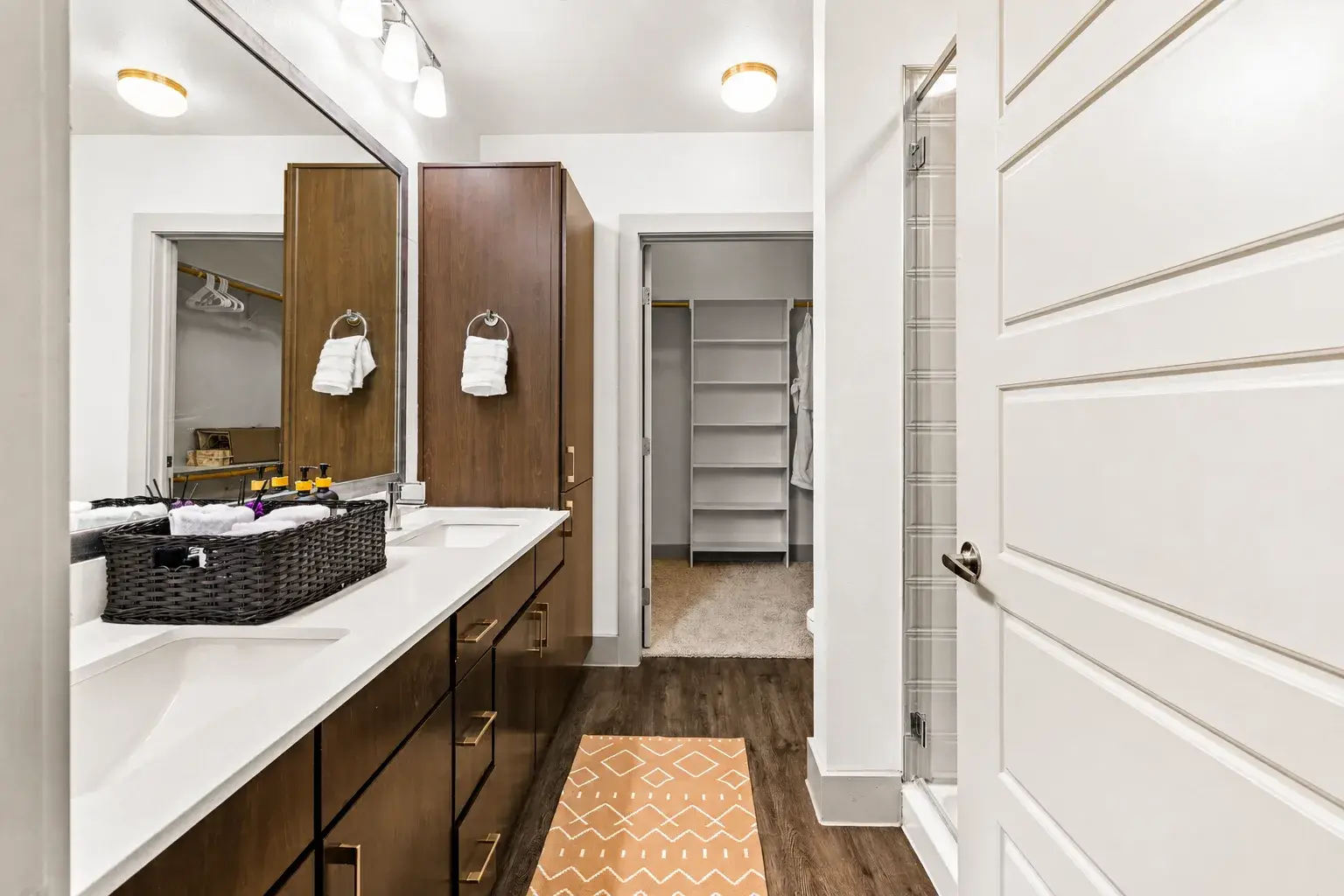 Spacious modern bath with double vanity, walk-in shower, and closet storage