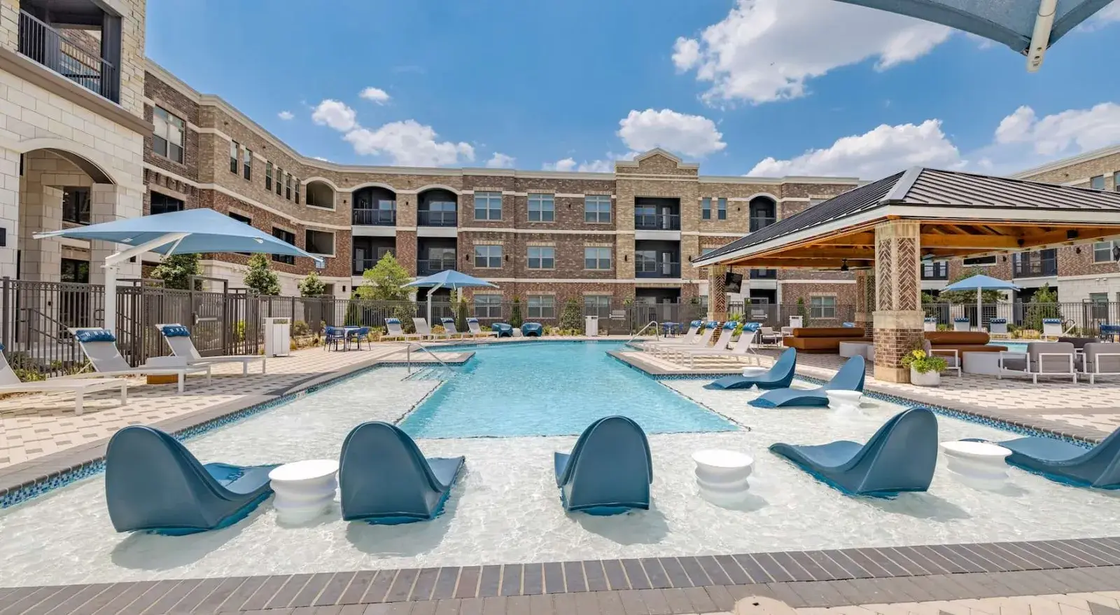 Resort-style pool with sun shelf loungers, cabanas, and pergola seating