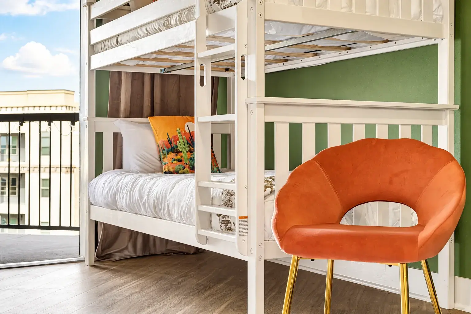 Bright bunk room with balcony access and a stylish accent chair