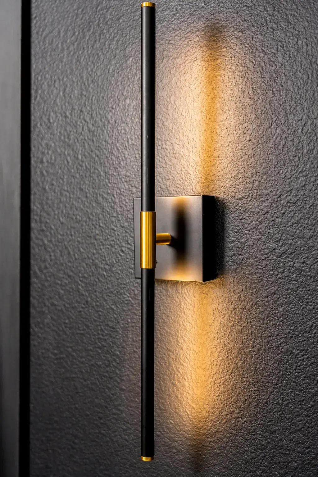 Modern black-and-brass wall sconce with warm ambient glow