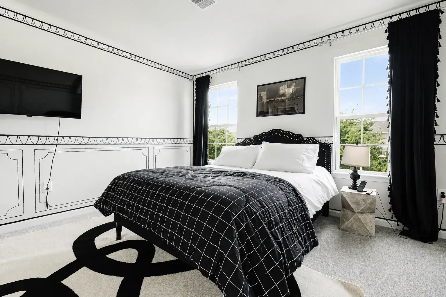 Chic black-and-white bedroom with natural light and wall-mounted TV