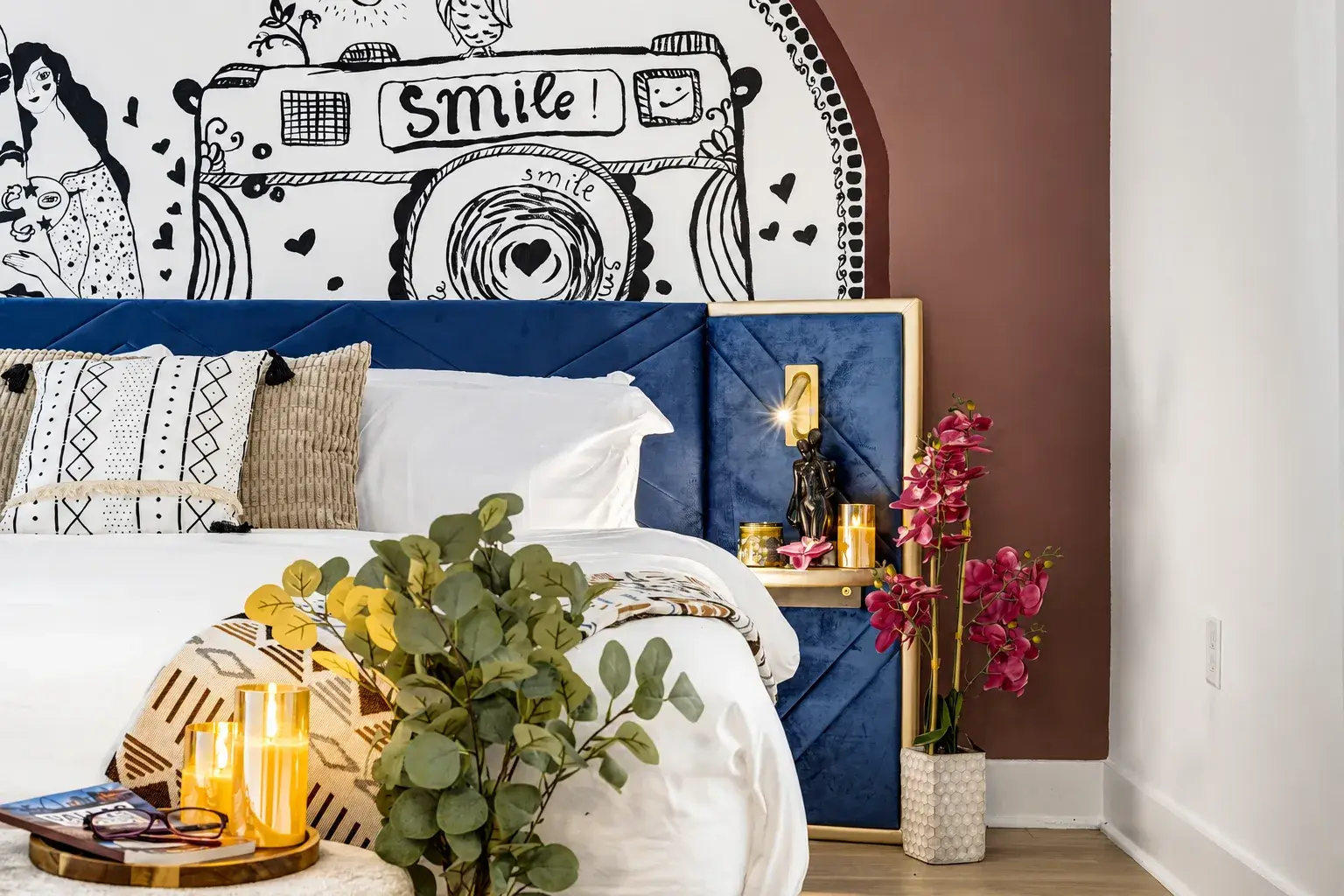Stylish bedroom with bold mural, luxe blue headboard, and warm accents