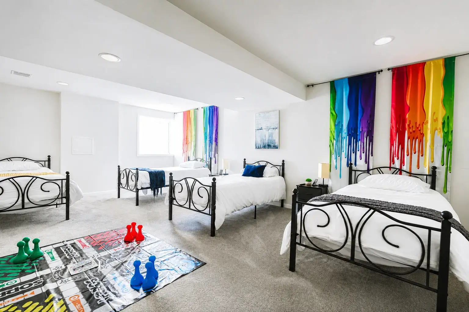 Spacious group-friendly bedroom with 4 beds, fun rainbow art, and games