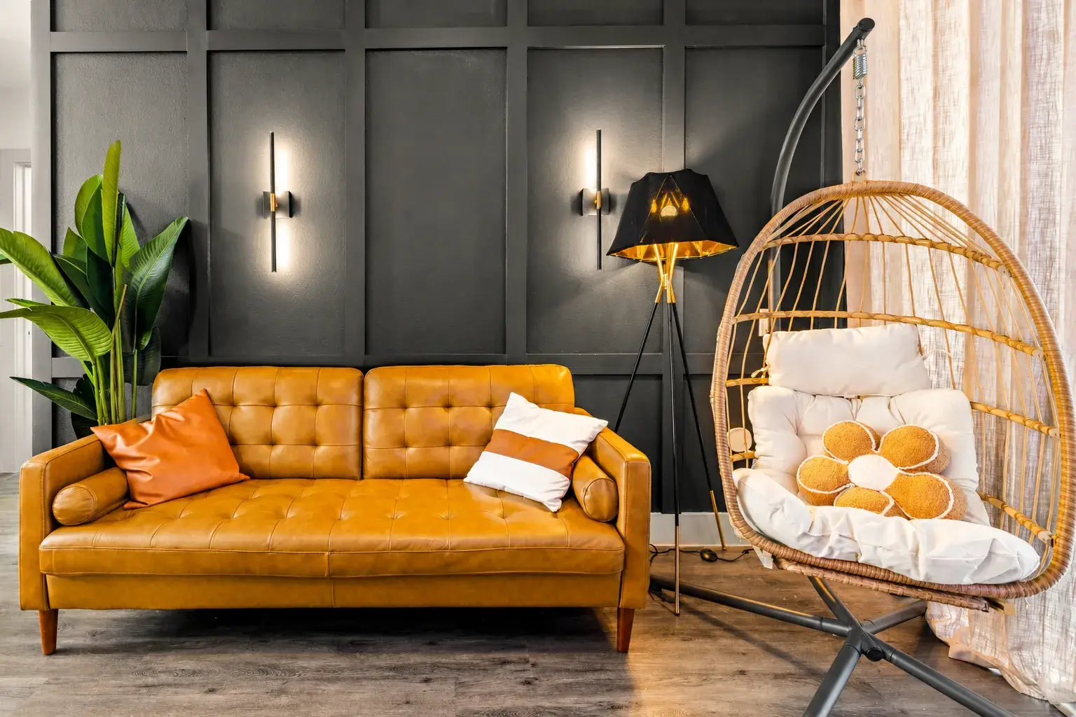 Chic lounge with leather sofa, black accent wall, and cozy hanging chair