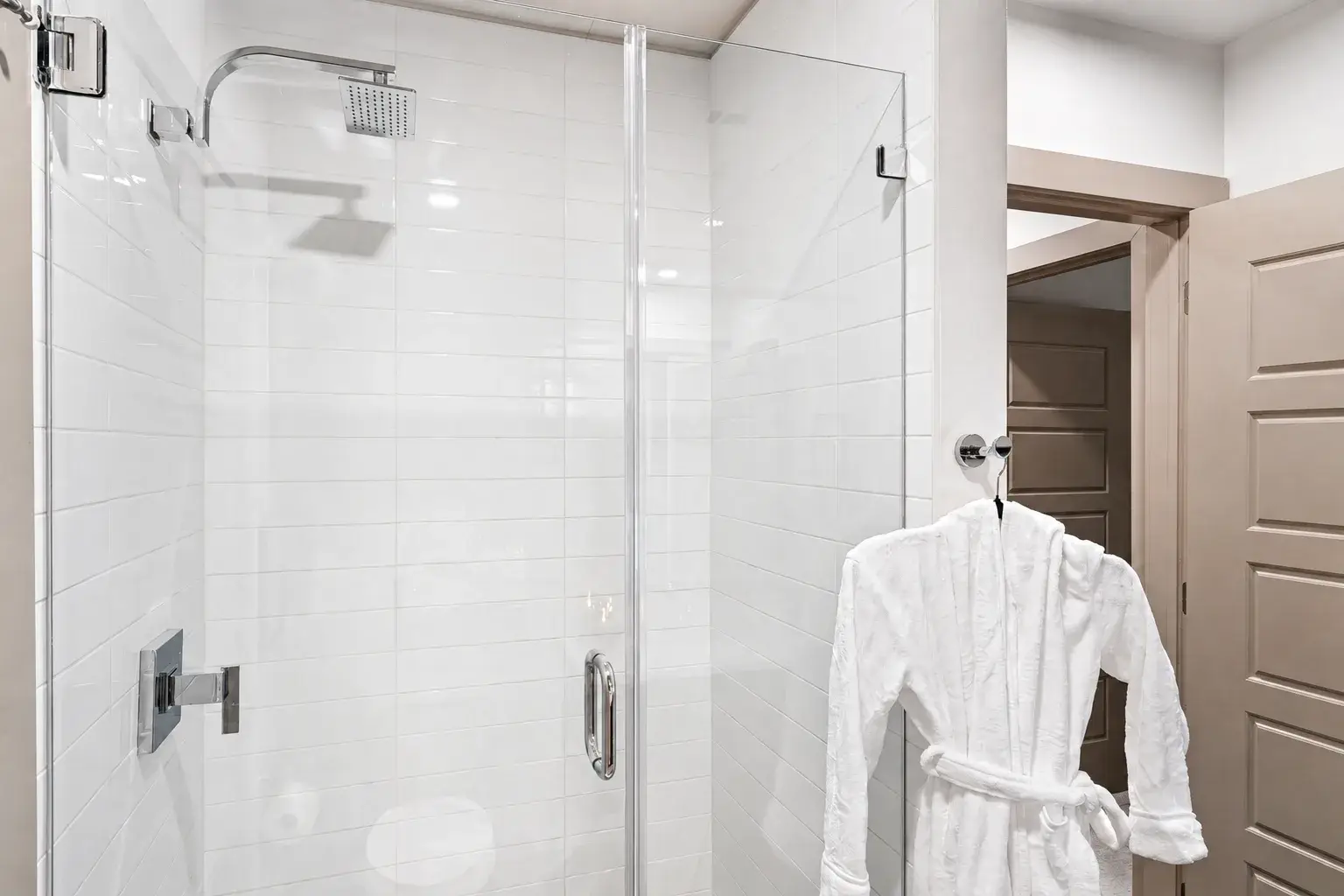 Spa-style glass shower with bright tile and plush robe