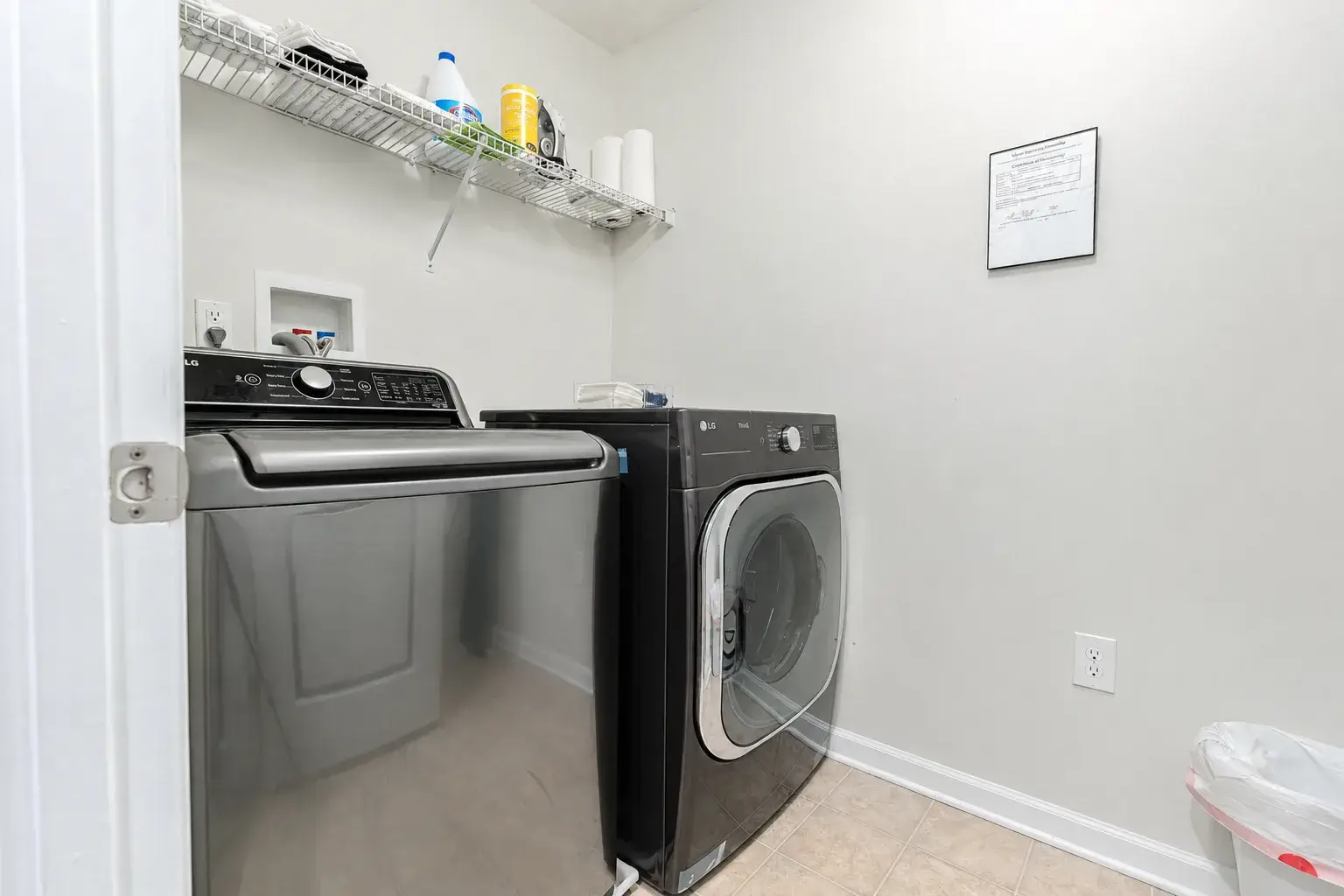 Convenient in-home laundry room with modern washer, dryer, and storage shelf