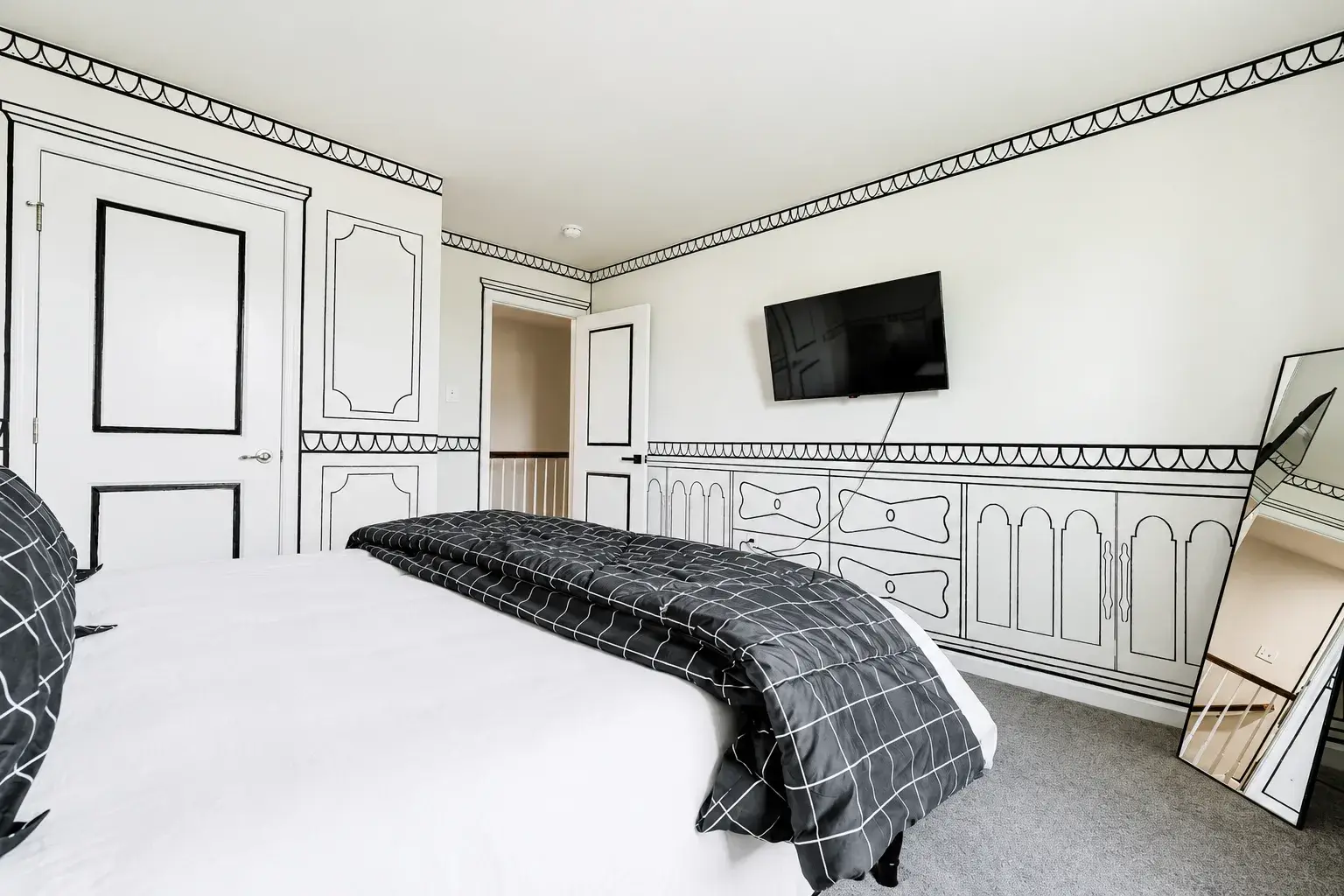 Stylish black-and-white bedroom with wall-mounted TV and artistic flair