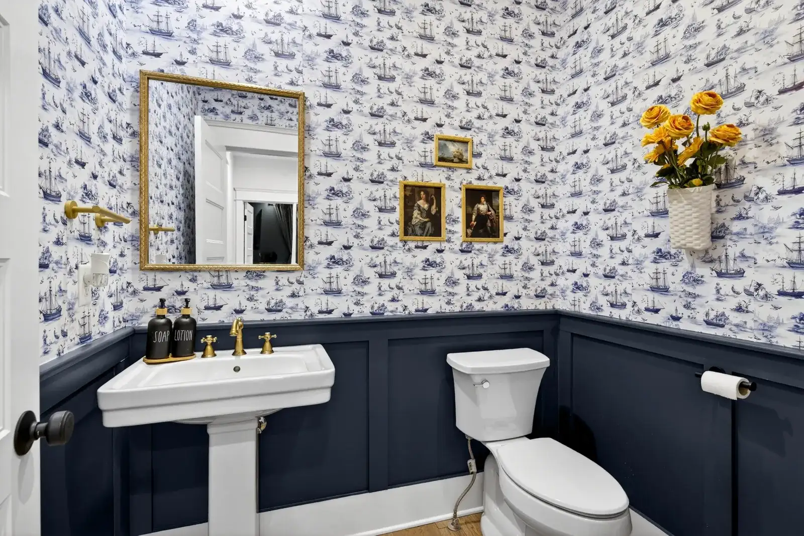 Charming nautical powder room with bold wallpaper and brass accents