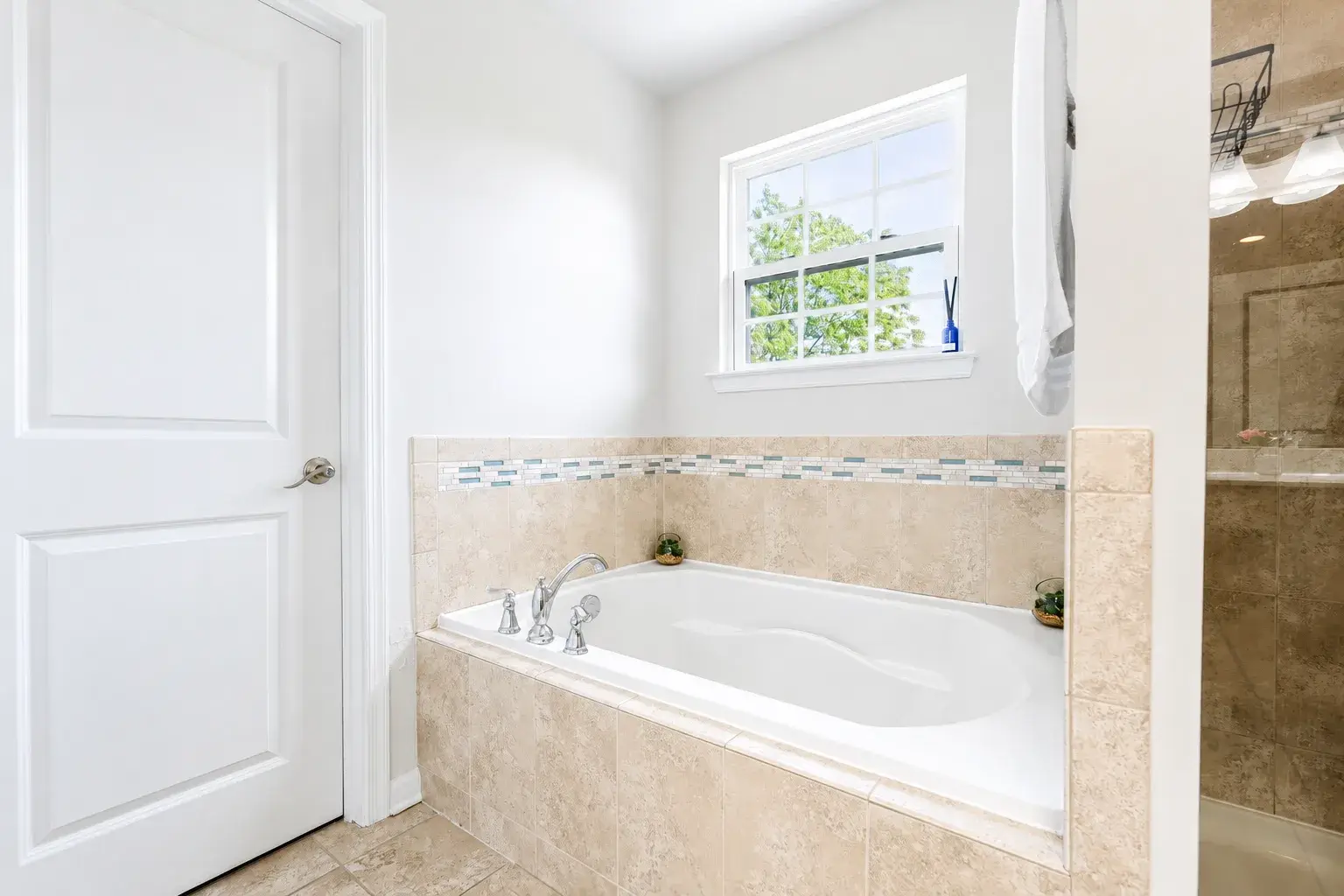 Bright spa-style bathroom with soaking tub, glass shower, and natural light