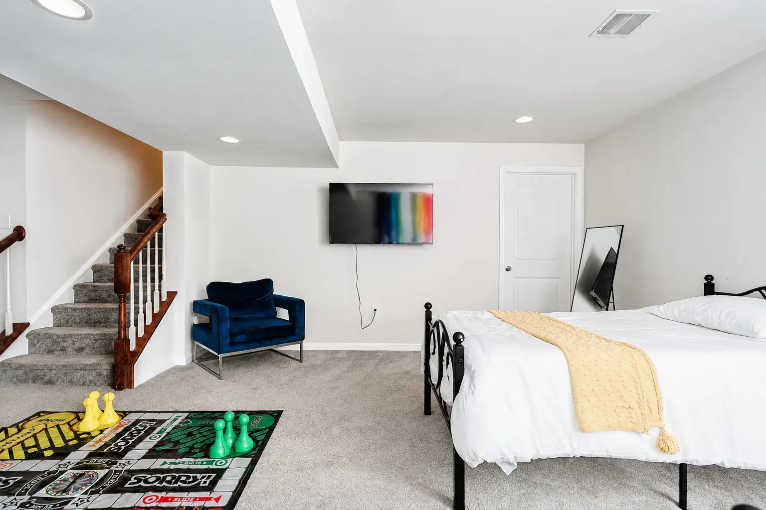 Spacious lower-level bedroom with TV, plush carpet, and fun game area
