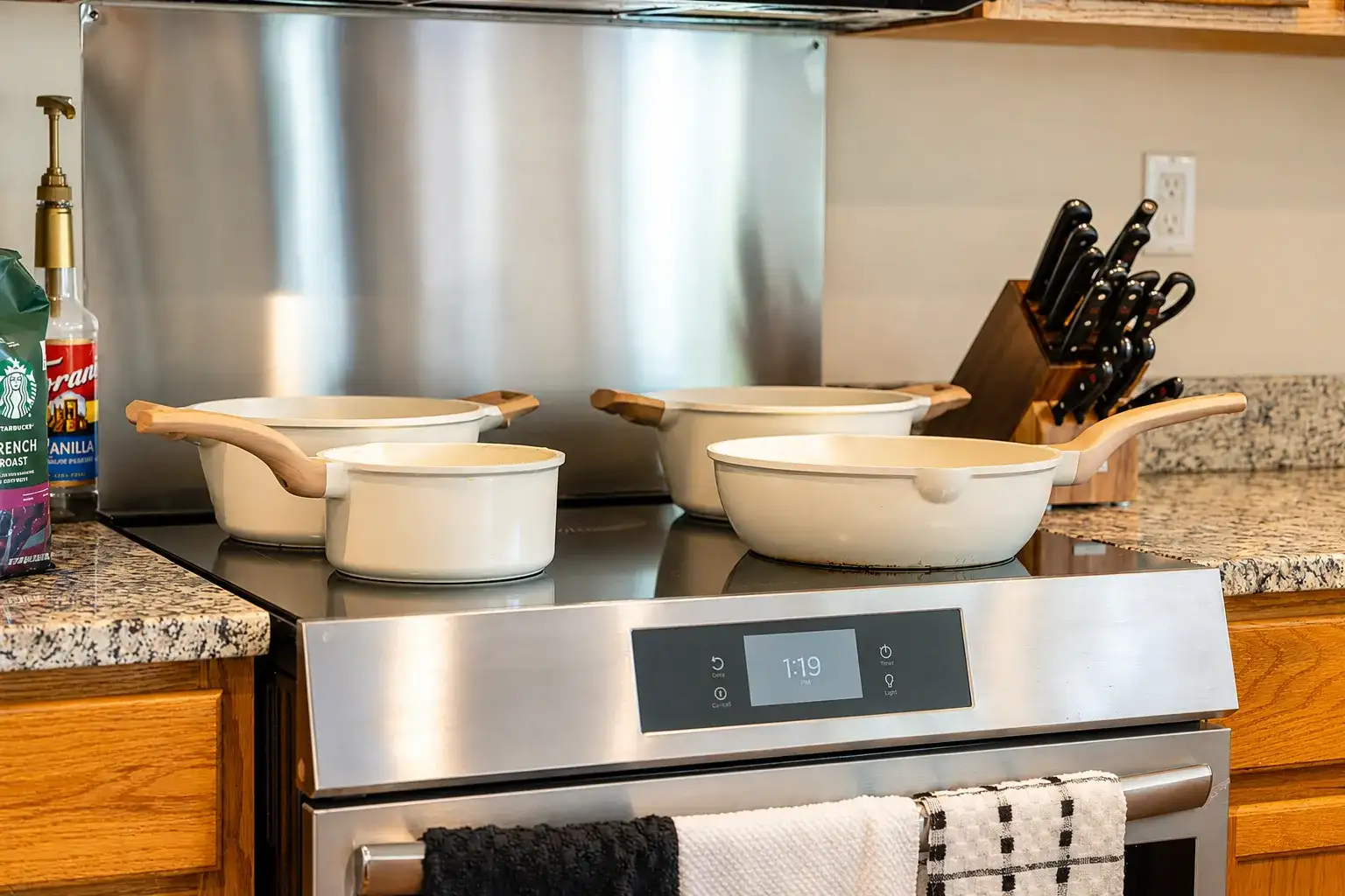 Well-stocked kitchen with modern stove, granite counters, and stylish cookware