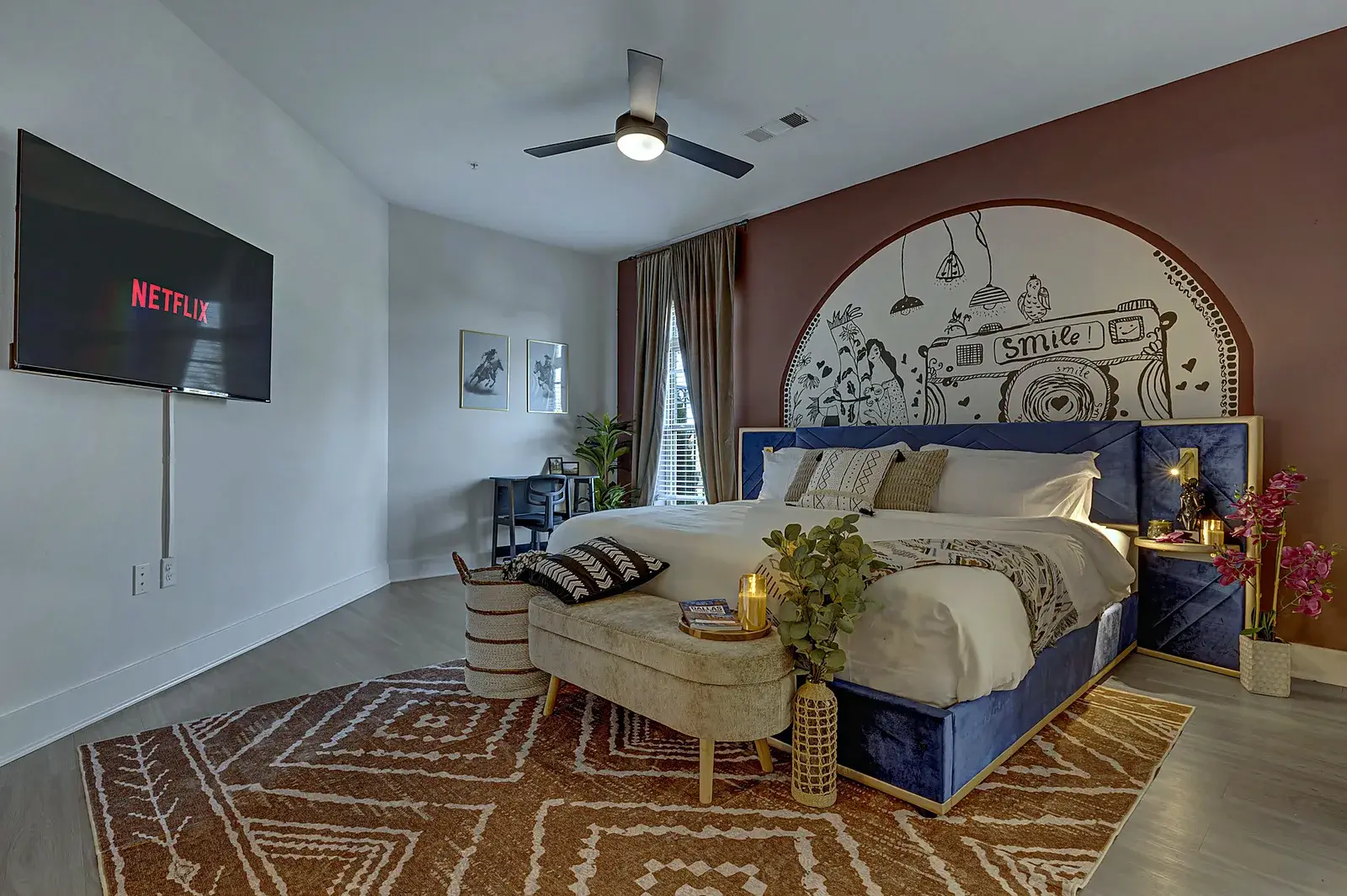 Boutique-style king bedroom with mural wall, smart TV, and cozy seating