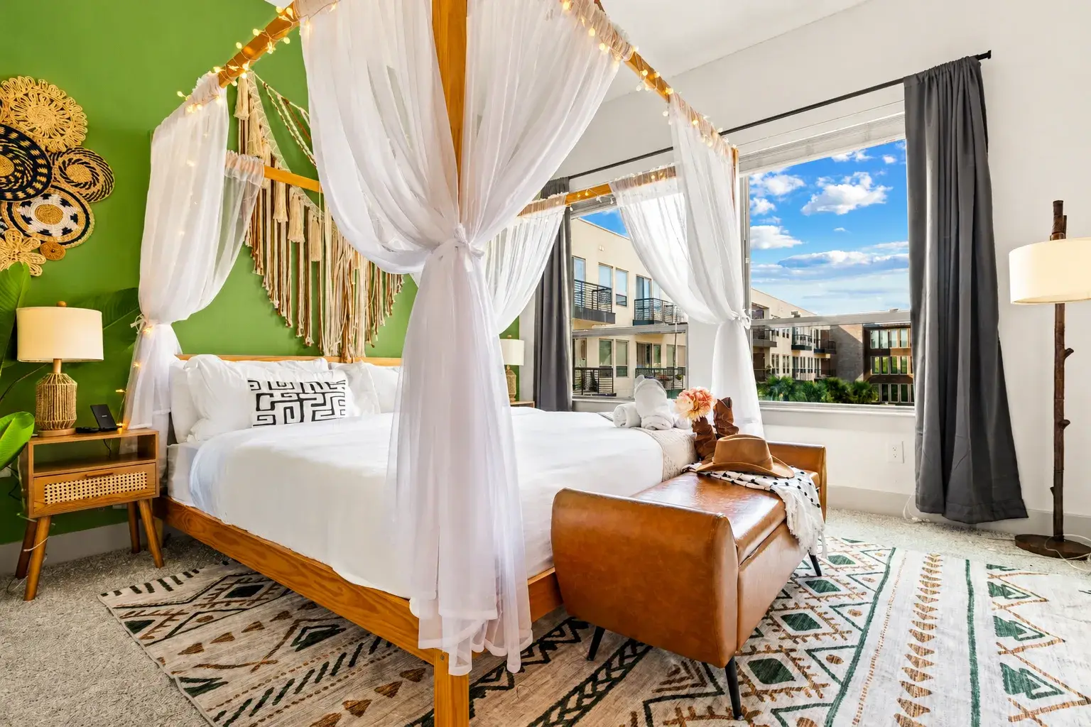 Bright boho bedroom with dreamy canopy bed and large sunny windows